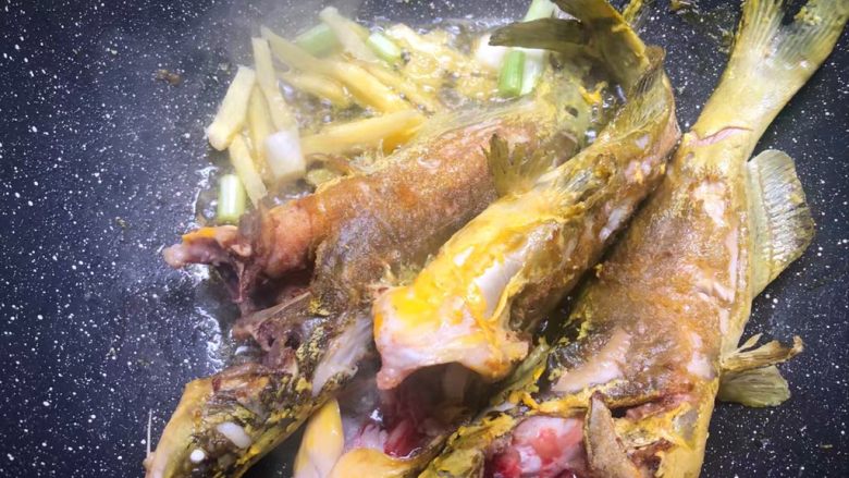黄骨鱼豆腐汤,待两面都煎好以后,把姜片和葱白放入爆香。