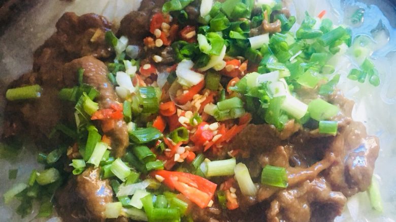 牛肉萝卜小火锅,把炒好的牛肉片,放入萝卜丝表面。 放入小小米辣和香葱碎。