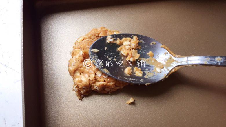 燕麦花生酱小小酥,取适量放烤盘上,用勺子背轻压整型。