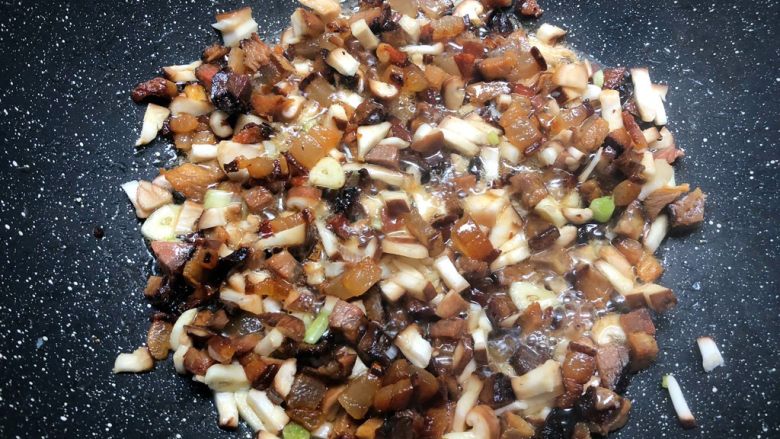 芥菜饭,肥肉煸出油以后,放入瘦的部分翻炒,再放入葱白和蒜末炒出香味,然后再放入香菇丁翻炒一分钟。