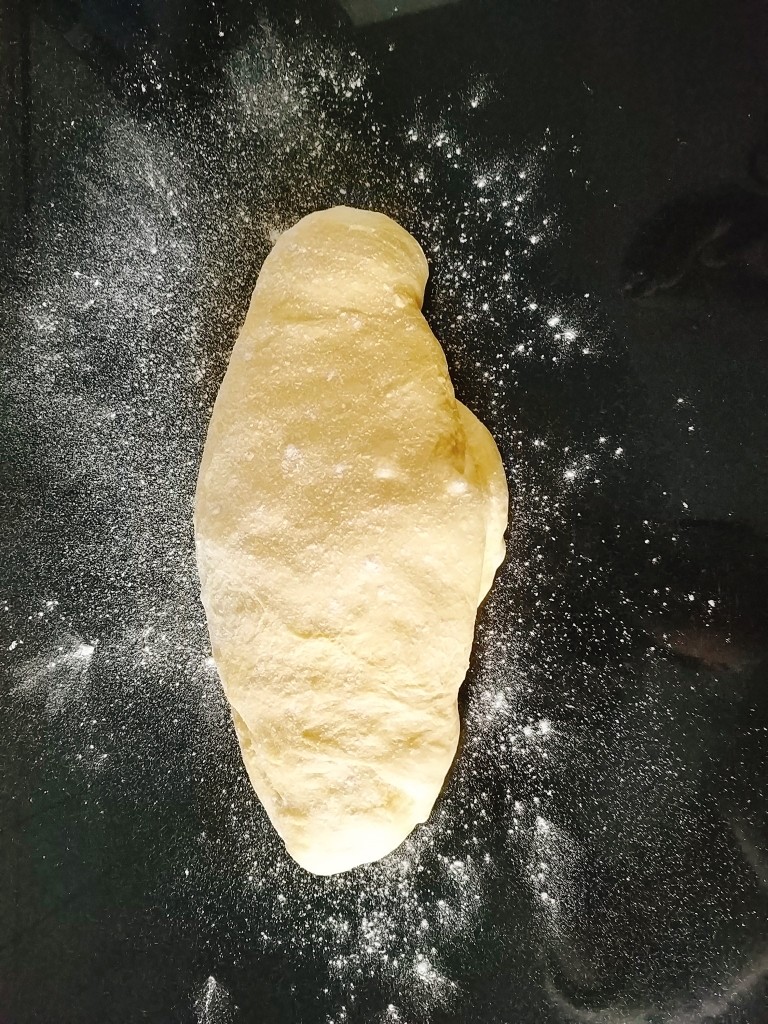 南瓜泥奶香吐司,发酵好的面团取出放在大理石操作台上轻撒一层干面粉防止粘手,用手轻压给面团排气,或者用擀面杖擀一下;