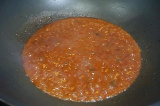 干锅鸡翅,锅内没有放油,直接放入郫县豆瓣酱,快速翻炒后倒入2大勺的料酒和蒜片炒匀。
