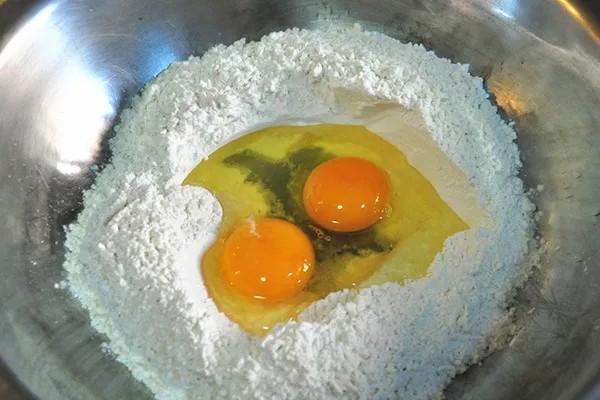 河南烩面,食用碱放入碗中,用清水化开,将面粉放入面盆中,打入鸡蛋,加入适量食用盐。