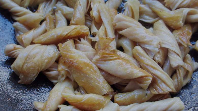自制辣条,锅中热油,加入豆筋煸炸金黄酥脆