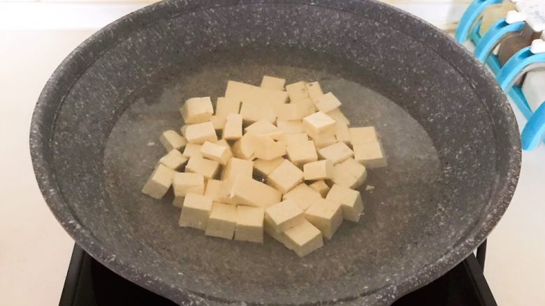 麻婆豆腐盖浇饭,先把北豆腐切成小块,锅里加入冷水,水开后加入豆腐块,焯水3分钟