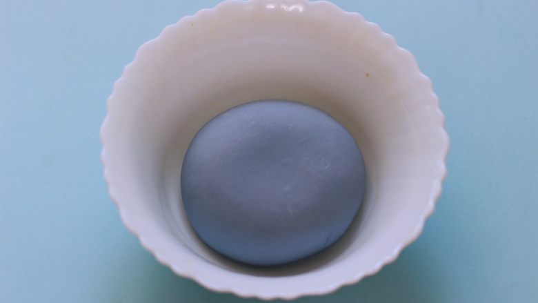 蝶豆花火腿肠花卷,和好的面团用手揉圆后,放入碗里盖上保鲜膜进行醒发。