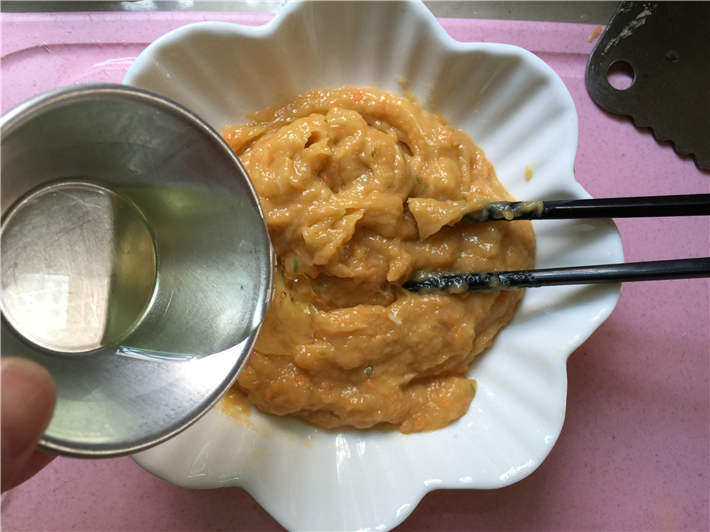 玉米鸡肉肠,倒入核桃油再顺着同一个方向搅拌均匀，至核桃油和肉糜相互吸收。