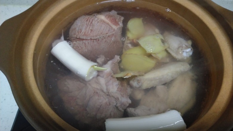 酱羊肉、牛肉、鸡翅炖土豆粉,砂锅中加入摸过肉的开水,加入葱段。