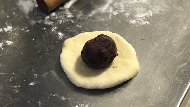 红豆面包,松弛后每份面团都擀成圆皮,然后放入一份红豆馅。