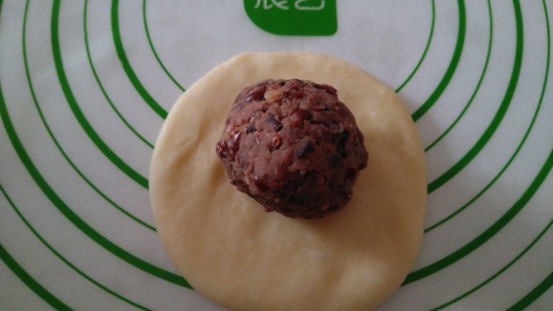 蒸豆沙面包,取一个剂子,用手压扁,放入馅料。