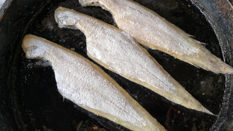 椒盐鳎米鱼,平底锅中适量的油烧热后,将拖好粉的鳎米鱼放入锅内,中小火煎。