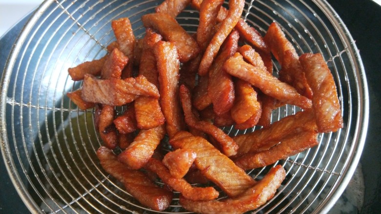 香辣里脊肉条 新文美食,过油炸制金黄熟透捞出来。