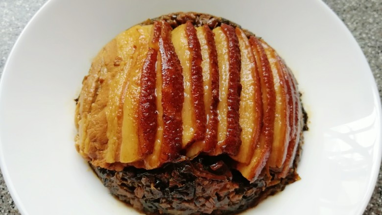 金牌天津扣肉,取出天津扣肉,将多余的汤汁滗出来倒回锅中再次浓缩,用水淀粉勾芡,把天津扣肉的碗上面盖上一个盘子,迅速将盘子翻个面,梅菜扣肉就反扣在了盘中。