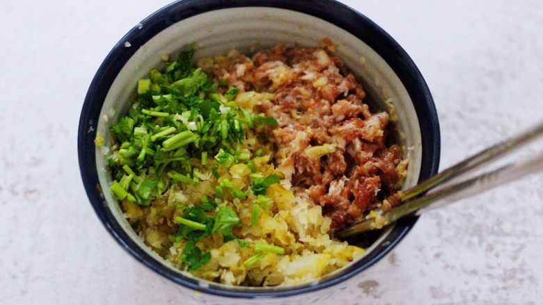 酸菜猪肉粉嫩饺子,把切碎的酸菜和香菜放入搅拌好的肉馅里。