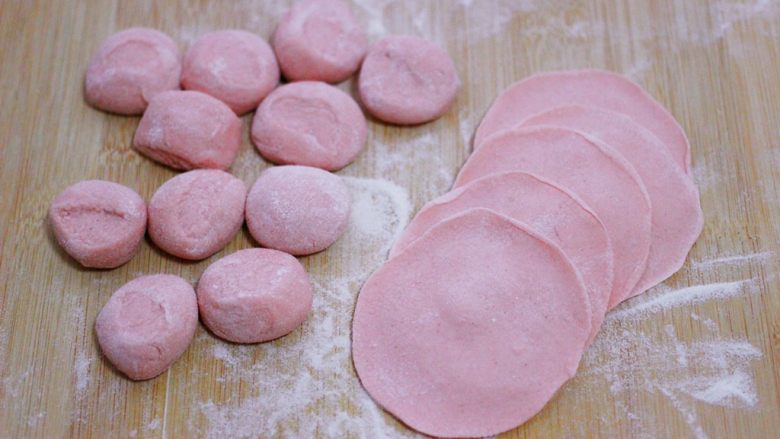 酸菜猪肉粉嫩饺子,把剂子用手摁扁,用擀面杖把剂子擀成圆形薄面皮。