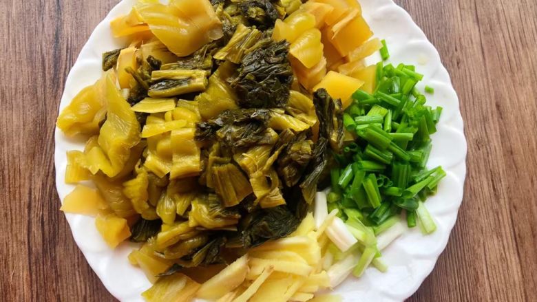 酸菜炖黄鱼,酸菜清洗干净切成段,生姜去皮清洗干净切成姜丝,葱清洗干净切成段。