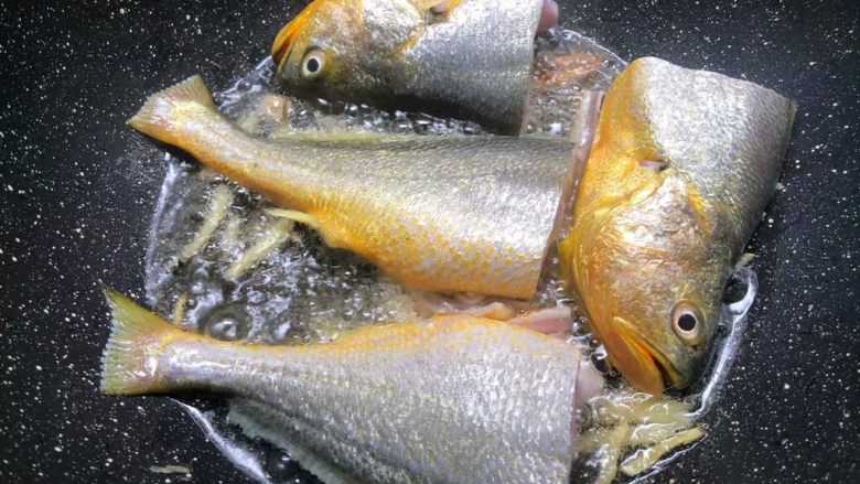 酸菜炖黄鱼,锅里放入适量油,烧至8成热,把姜丝放入爆香,再把黄鱼放入煎制。