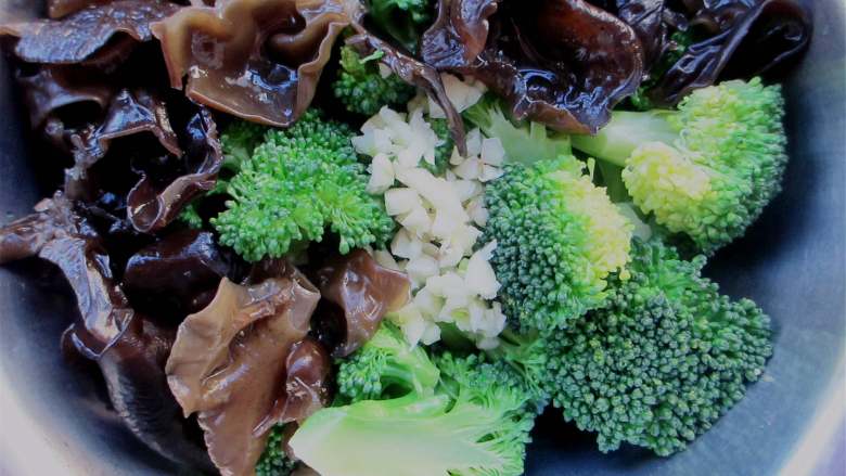 西兰花拌木耳,木耳和西兰花放在一起,加入盐、鸡精、醋、味极鲜酱油,撒上一把蒜末、辣椒面
