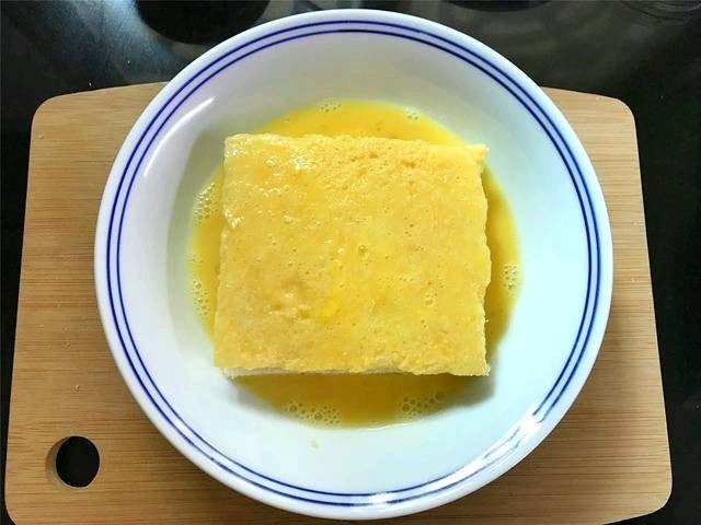 芒果酸奶土司,把夹入水果的吐司放入鸡蛋液中,上下和四周都均匀地裹上一层蛋液.