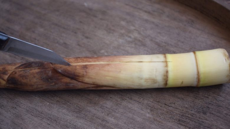 春天的美味 腌笃鲜(鸡肉版),先用刀把春笋的老根切下去,再用刀在春笋的表面轻轻的划一刀,沿着刀缝处用手往两边掰,春笋的外衣就能很轻松的剥下来了。