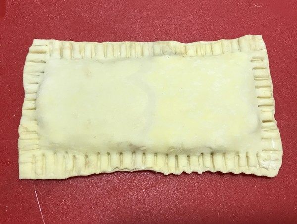 红豆派,盖上另一半,四周捏严,用叉子压出花纹。
