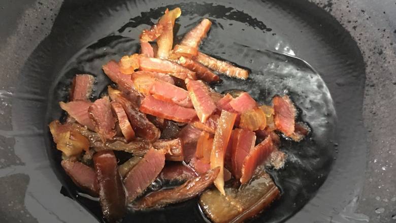 烟熏腊肉炒芹菜,锅里放入少许的油,放入腊肉,小火翻炒至肥肉出油
