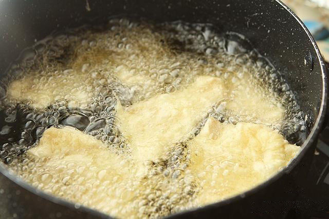 锅包肉,锅内放入适量油,油热后转中火,夹起肉片后停一下让多余的面糊滴落后放入锅内炸,炸到定型后捞起;