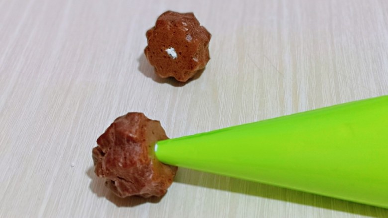 巧克力奶油泡芙,这时泡芙也凉了,用筷子捅个小洞洞,再将裱花嘴插入洞洞里,挤入奶油即可。