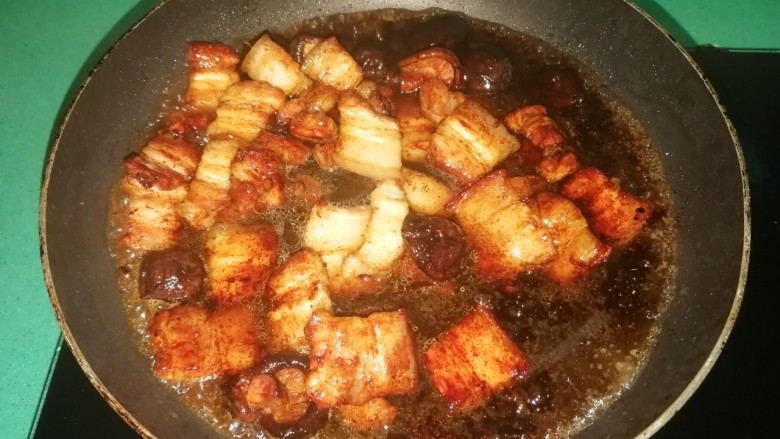 五花肉焗南瓜,倒入泡香菇的水,盖上盖子焖至汤汁浓稠