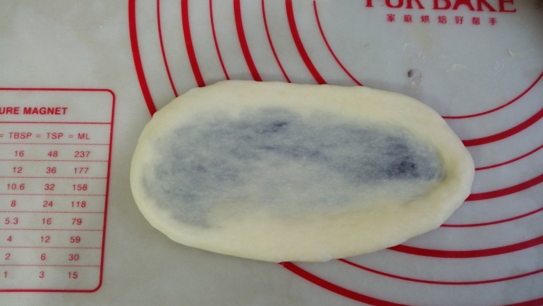 紫薯花面包,将面团略用手压扁后,用擀面棍擀成椭圆形