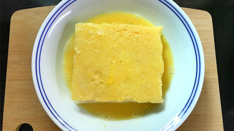 芒果酸奶吐司,把夹入水果的吐司放入鸡蛋液中,上下和四周都均匀地裹上一层蛋液。