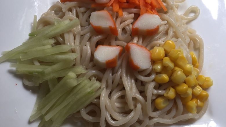花生酱凉拌面,盘子里放入煮熟的面条,再放上备好的配菜;