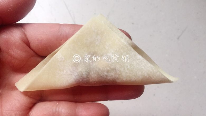 上海三鲜小馄饨,现在还有一种简单包法,因为包好后的外形象金鱼,所以被叫做金鱼馄饨。同样用筷子挑适量的肉馅放在馄饨皮中心位置,用筷子辅助对折成三角状(不用捏牢的,只需要随意地把皮子翻上去成三角状就可以了。)