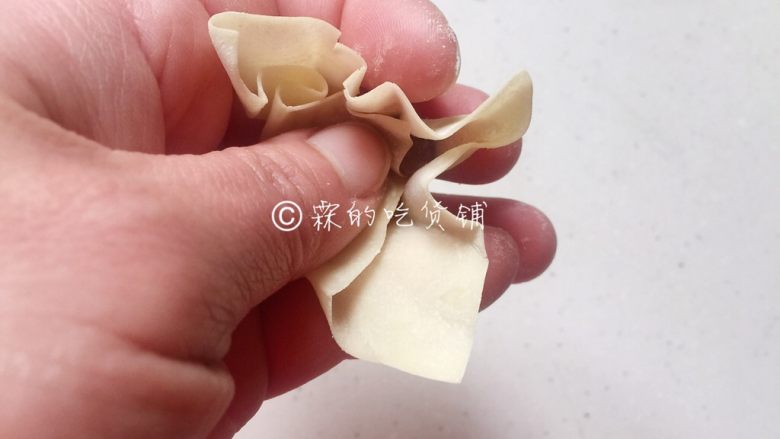 上海三鲜小馄饨,传统小馄饨的包法,用一根筷子挑适量肉馅放在馄饨皮中心位置,然后先把大拇指这边的皮捏下去。