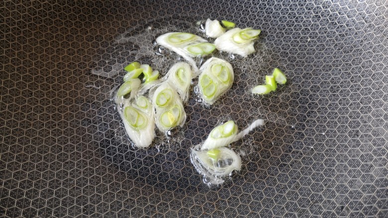 葱油腊味鲜蚕豆,锅中倒入适量油,中大火加热,把葱花放进来煸炒,一直炒到葱香味出来。