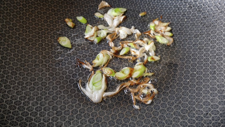 葱油腊味鲜蚕豆,等葱花变成这样的棕黄色,再煎一会儿。
