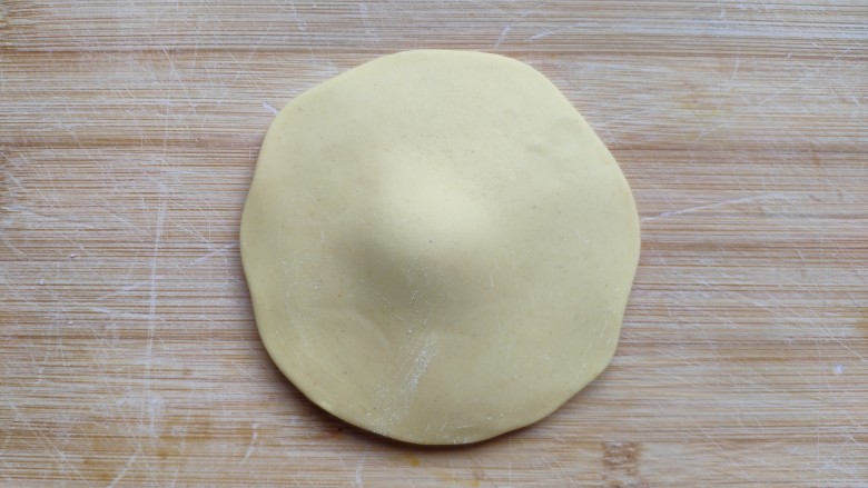 土豆造型豆沙包(馒头),取一个黄面团先揉光滑,擀成四周薄中间厚的面皮。