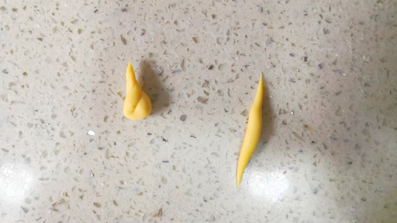 零色素卡通馒头可爱独角兽馒头,取大概1.5g黄色面团搓成如图右边两头尖的形状,然后对折扭麻花一样扭一起。如图左边形状。这样就做好一个独角兽的角了。一共做四个。面团重量只是参考,实际可以随手操作。