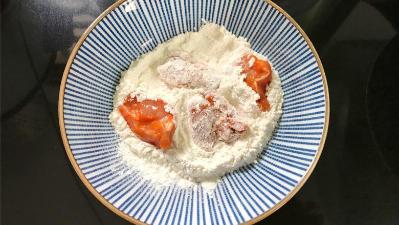 香辣鸡米花,然后取一块鸡肉,先裹一层淀粉。