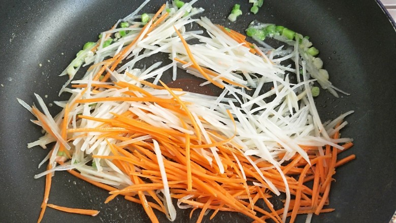 土豆丝火腿鸡蛋饼,倒入土豆丝。胡萝卜丝炒软。七八成熟。最后倒入火腿丝,翻炒两下盛出待用