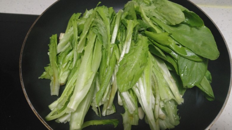 冻豆腐炒油麦菜,用手将油麦菜拧成两半，放入锅中。