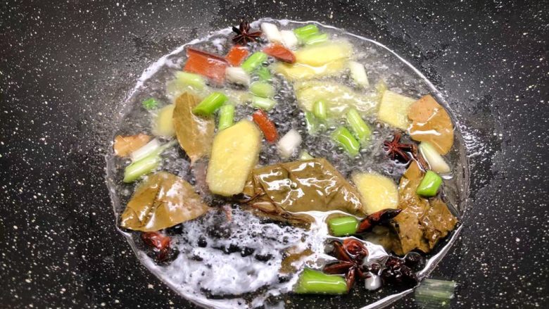 萝卜烧牛腩,锅里放入适量油,先把葱白和姜片放入炒出香味,再把八角、桂皮、香叶放入炒香。