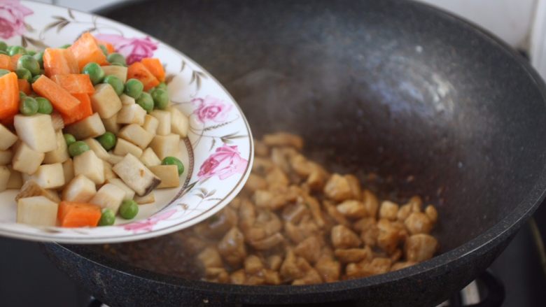 鸡丁炒豌豆杏鲍菇,翻炒均匀鸡丁后放入杏鲍菇和胡萝卜、豌豆。