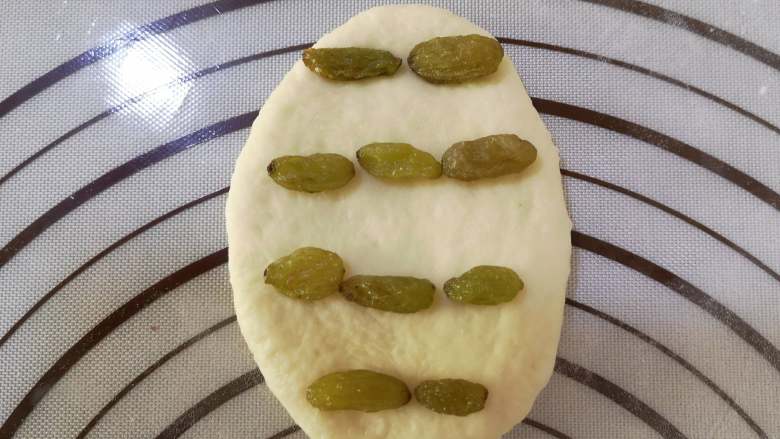 葡萄干小面包,取出一个小面团,用擀面杖将小面团擀成圆形或椭圆形,将葡萄干均匀地铺在面片上。从面片的上部往中间折,下部往中间折,再将两侧向中间折,最后将收口处用虎口捏紧,整理成圆形即可。