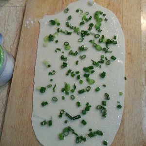 葱油饼,擀成长方形薄面皮。淋上食用油适量,均匀撒上葱花和盐;
