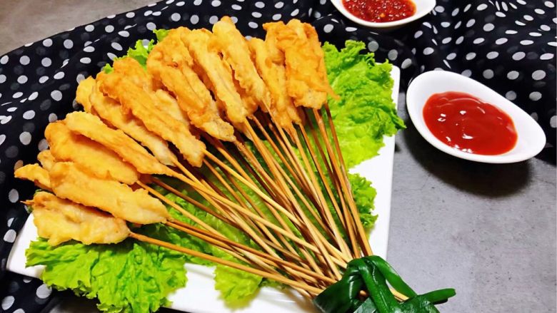 鸡肉串串香,盘中摆上生菜再把鸡肉串串用韭菜捆起来摆在盘中搭配番茄酱和蒜蓉辣椒酱