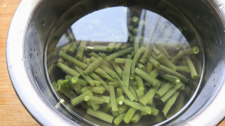 凉拌豆角,再切成1寸左右的长度,锅里加入适量的清水,烧开后把豆角焯水断生,焯水的时候在锅里放少许盐,这样豆角就会变在翠绿色,很漂亮,