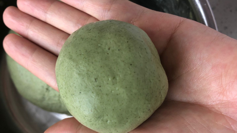 青团,用手将皮沿着馅料往中间推,直至完全收口,搓成圆球。青团总重量是75克/个,不想揉成圆球,可以用80克的月饼模具,压出好看的花型。