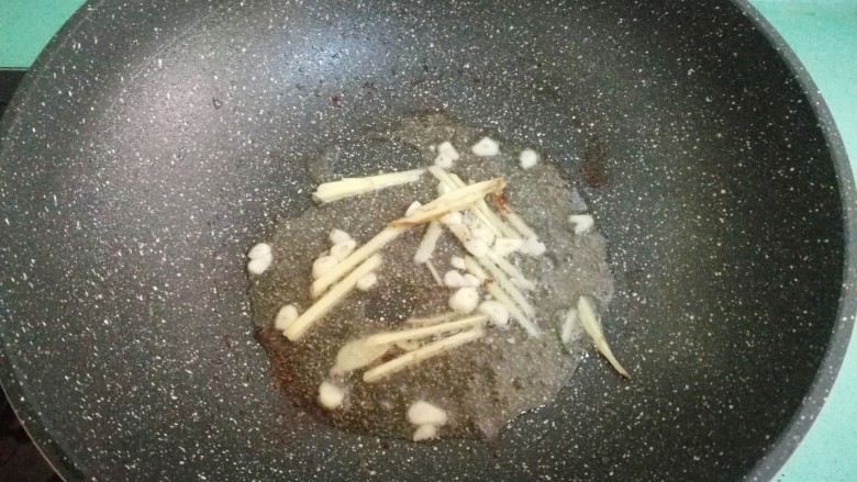 酒酿烧带鱼,锅里的油不用换掉,直接放入姜丝和蒜瓣,爆出香味