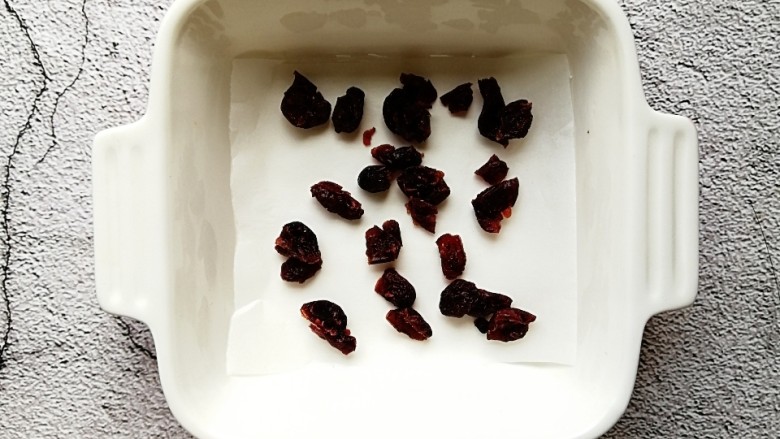 蔓越莓酸奶糕,取一个容器,铺上一层油纸,撒上切碎的<a style='color:red;display:inline-block;' href='/shicai/ 660'>蔓越莓</a>